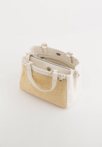 Gevlochten tan stro en witte faux leren handtas met twee handgrepen, een gerimpelde bovenkant, en een ritscompartiment binnenin.