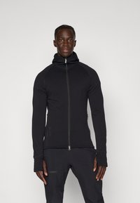 Black zip-up athletic hoodie with a high collar, made of a stretchy, textured fabric. Features fitted sleeves and side zip pockets.