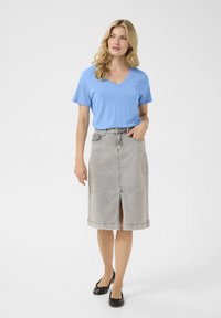 Vaaleansininen V-kaula-aukkoinen t-paita yhdistettynä polvipituiseen harmaaseen farkkuhameeseen, jossa on edessä halkio ja viisi kätevää taskua. Mustat ballerinat täydentävät asun.