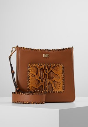 Brun læder crossbody taske med forlommelomme med slangeprint, whipstitch-detaljer, bred rem og gyldt MK-logo på ensfarvet baggrund.