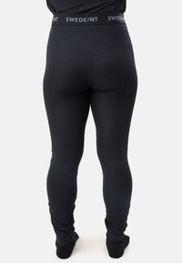 Svarta leggings med ribbat mönster, som har en högmidjad design och en midja märkt "SWEDENT". Släta, åtsittande, ankellånga.