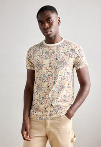 Kortærmet t-shirt i letvægtsstof; prydet med et multicolor geometrisk mønster i nuancer af beige, orange, sort og accenter af creme.