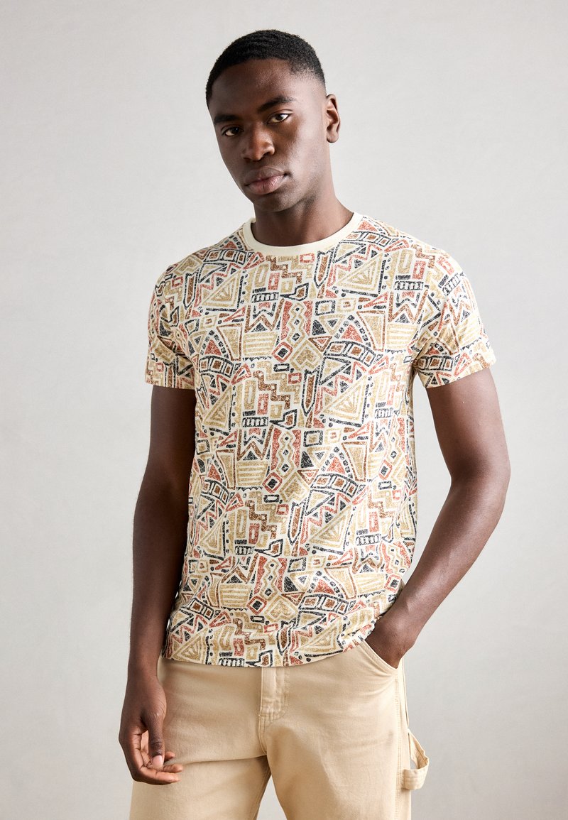 Kortærmet t-shirt i letvægtsstof; prydet med et multicolor geometrisk mønster i nuancer af beige, orange, sort og accenter af creme.