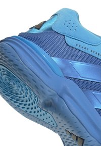 Gros plan sur la semelle d'une chaussure de sport bleue et la partie supérieure en mesh avec grip texturé et texte "Court Stable" sur le côté.