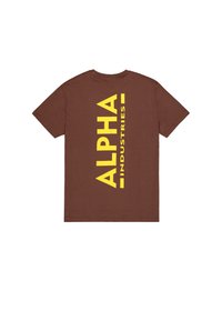 Καφέ κοντομάνικο T-shirt με μεγάλο κατακόρυφο κίτρινο κείμενο "ALPHA INDUSTRIES" τυπωμένο στην πλάτη.