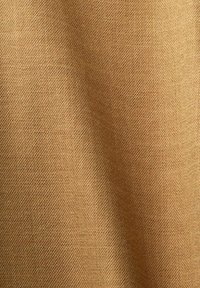 Tan cotton fabric with a textured weave. The surface appears slightly uneven, creating a soft, natural look.