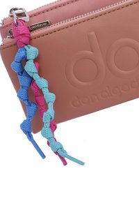 Bolso sintético rosa con cremallera que presenta un logotipo en relieve, adornado con un llavero trenzado en colores azul, rosa y aqua.