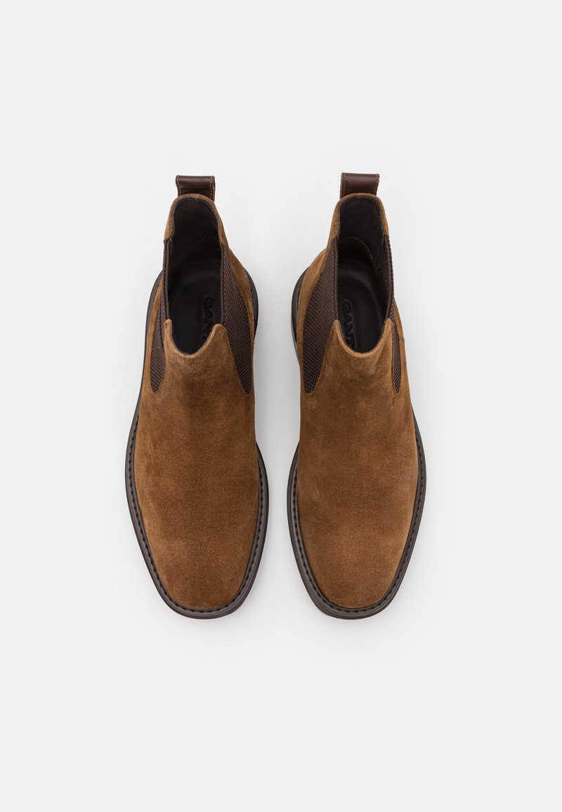 Bottines en suede marron avec des panneaux latéraux élastiques, un bout arrondi lisse et un talon texturé contrastant. Dotées d'une languette pour un enfilage facile.