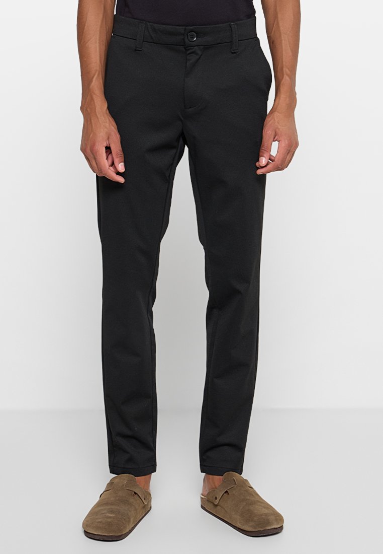 Schwarze maßgeschneiderte Hose mit Slim-Fit, ausgestattet mit einem vorderen Knopfverschluss, Gürtelschlaufen und seitlichen Taschen, aus einem glatten Stoff gefertigt.