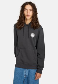 Sudadera con capucha de color gris carbón, con cordones, bolsillo canguro frontal y un logo circular en el pecho. Textura suave y ajuste casual.