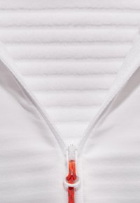 White zip-up garment with a ribbed, textured interior. Features a silver zipper with an orange pull tab, providing contrast and functionality.