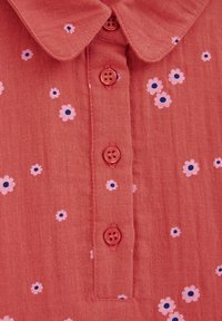 Korálová textilní košile s límcem, pěti růžovými knoflíky a květinovým vzorem s růžovými a námořnickými akcenty. Lehká tkanina.