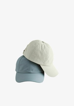 Két egyszerű baseballsapka egymásra helyezve, egy világos bézs a tetején és egy tompa kék alul, fehér háttéren bemutatva.