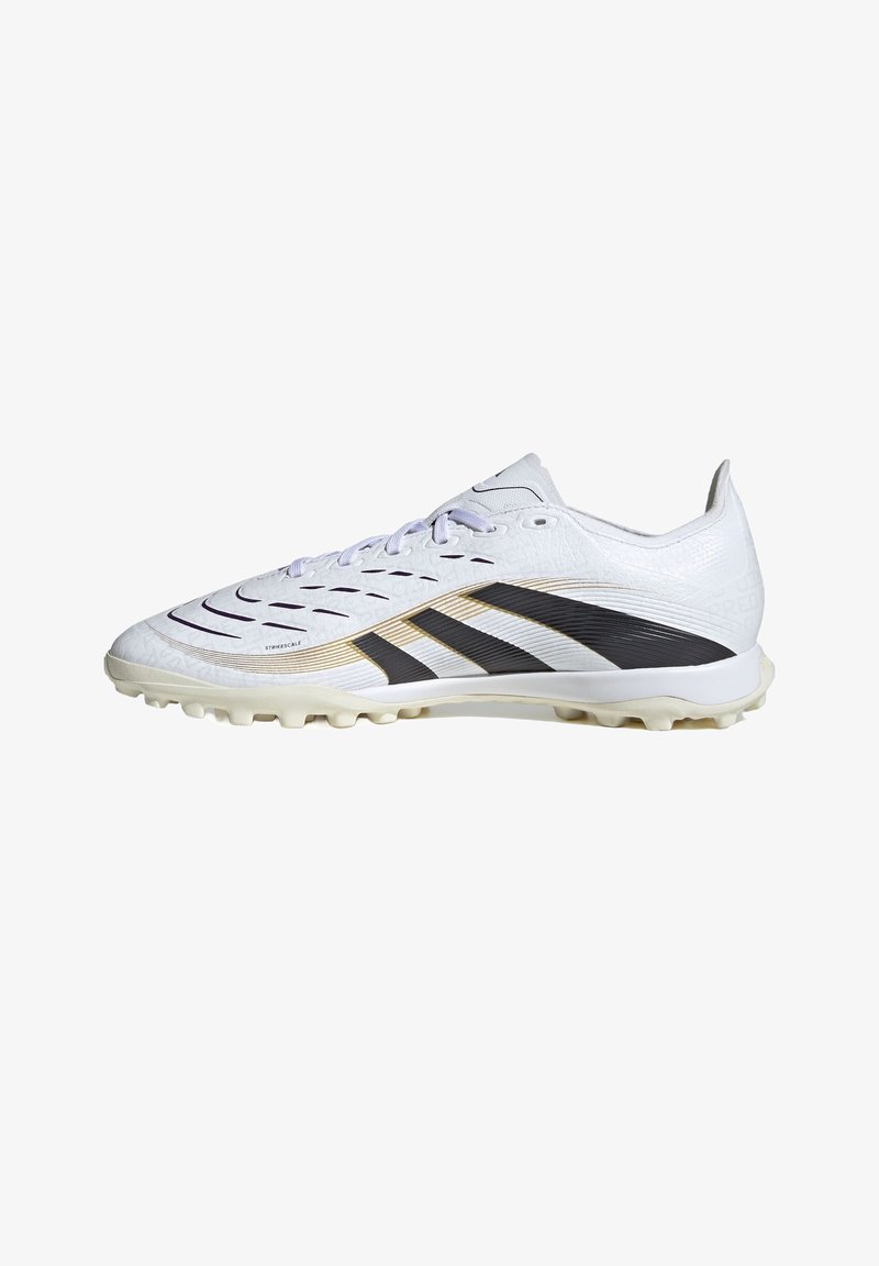 Bílý fotbalový kopač s texturovaným syntetickým svrškem, černými a zlatými akcenty a gumovými kolíky na podrážce pro lepší přilnavost. Šněrovadla jsou světle fialová.