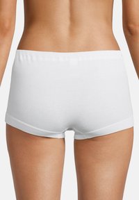 Vista posteriore di una persona che indossa una mutanda boyshort in cotone bianco semplice su uno sfondo neutro.