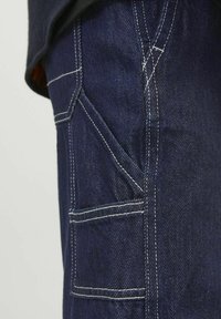 Temno modri jeans z kontrastnim belim šivom in dvema žepoma na straneh. Tkanina ima gladko, klasično teksturo.