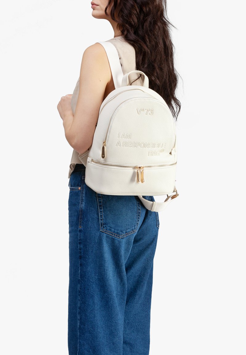 Zaino in pelle bianca con testo impressato "IO SONO UNA BORSA RESPONSABILE" e dettagli in oro, caratterizzato da una forma arrotondata e dettagli con zip.