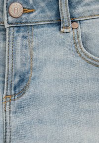 Helle blaue Jeans mit orangefarbener Naht, ausgestattet mit einem Metallknopf mit "Blue Ridge"-Markierung und einem Fronttaschen-Detail.