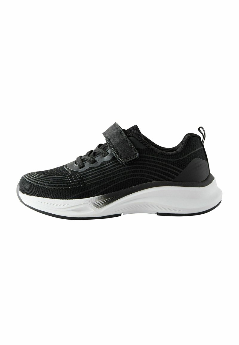 Chaussure de sport noire avec une tige texturée, semelle blanche et sangle velcro. Caractéristiques d'un design épuré avec de subtils motifs linéaires le long des côtés.