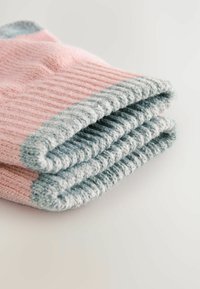 Gefaltete, rosa und hellblaue gestrickte Socken mit geripptem Muster und kontrastierenden Rändern, die auf einer hellen Oberfläche liegen.