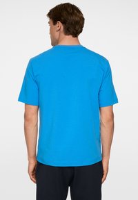 T-paita, jossa on lyhyet hihat ja pyöreä kaula-aukko, kirkasta sinistä puuvillakangasta. Paidassa on yksinkertainen malli ilman kuvioita tai koristeluja.