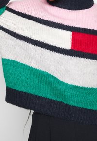 Multifarvet cropped trøje med horisontale striber i pink, rød, hvid, grøn og marineblå. Strikket tekstur med ribbet kant.