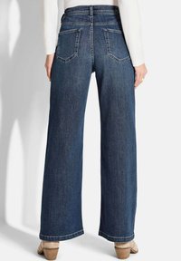 Jeans en denim bleu à jambes larges avec une taille haute, dotés de deux poches arrière et d'un ourlet net. Le tissu est légèrement texturé et de poids moyen.