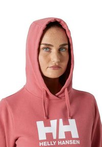 Sudadera rosa hecha de tejido suave; presenta un gran logotipo blanco "HH" y cordones en la capucha; textura suave con un corte holgado.