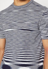 Kortärmad T-shirt med horisontella marinblå och vita ränder, med ett subtilt gradientmönster och rund halsringning. Tillverkad av mjukt tyg.