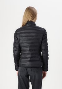 Sort puffet jakke med horisontale søm, høj krave og slim fit. Materialet fremstår glinsende med en let, isoleret tekstur.