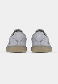 Gray leather sneakers with rounded backs, textured rubber soles, and embossed "85" details on the heel. Flat laces and cushioned collars.