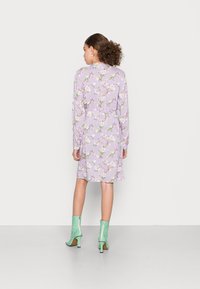 Vestido lilás com padrão floral, mangas longas, cintura ajustada e saia fluida, combinado com botins verde menta com zíper.