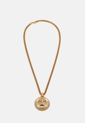 Collar de cadena de oro con un colgante redondo que presenta un diseño de cabeza de león en relieve y un borde texturizado, exhibiendo un acabado de metal pulido.