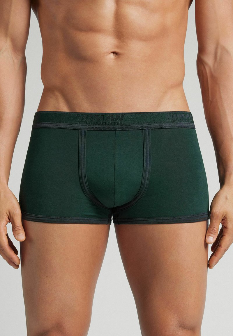 Boxer ajustados de color verde oscuro, hechos de material suave, con una cinturilla elástica negra con marca y un diseño ceñido con costuras en contraste.