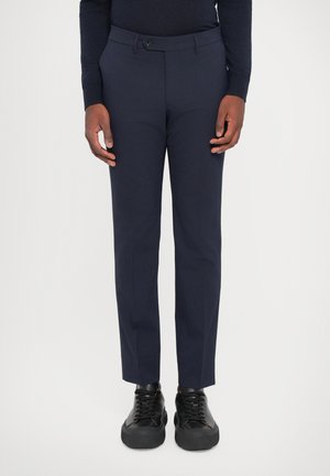 Pantaloni su misura blu navy realizzati in tessuto liscio, con chiusura a bottone, taglio slim e abbinati a sneakers nere.