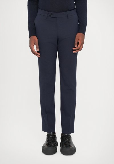 Marineblauwe op maat gemaakte broek van gladde stof, met een knoopsluiting, slim fit en gecombineerd met zwarte sneakers.