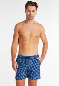 Maillot de bain bleu avec un motif géométrique, taille élastique avec cordon de serrage, poches latérales, en tissu léger et de longueur mi-cuisse.
