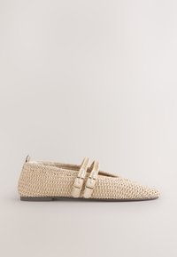 Chaussure plate tissée beige avec bout pointu et deux brides crème avec boucles dorées sur un fond clair uni.
