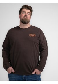 Lange bruine katoen t-shirt met lange mouwen, voorzien van een klein oranje logo op de linker borst, met een ronde hals en een casual pasvorm.