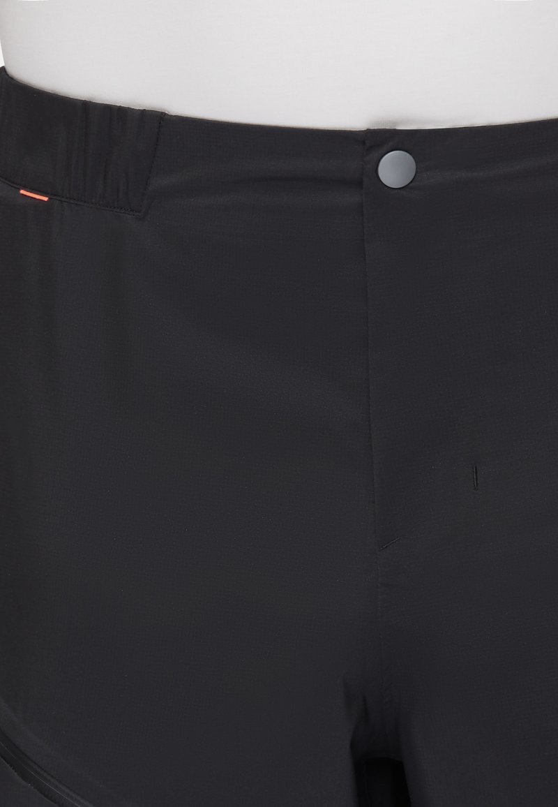 Shorts de sport noirs en tissu lisse et léger, avec une taille élastique et une fermeture à un bouton. Une petite ligne d'accent orange est visible.