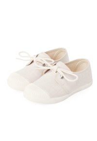 Des chaussures en toile beige clair avec un bout rond, une semelle en caoutchouc blanche et des lacets. Elles présentent des œillets en argent et un embout texturé.