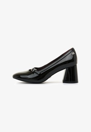 Zapato de charol negro tipo pump con punta redondeada, tirante en el tobillo y detalle de hebilla. Presenta un tacón cuadrado y robusto. Acabado liso y brillante.
