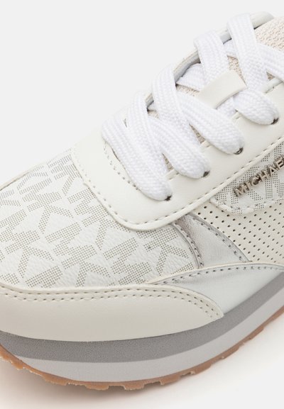 Hvite sneakers med teksturert lær, mesh-detaljer og tonet merkevare. Tykk hvit snøring og en lys grå gummisåle fullfører designet.