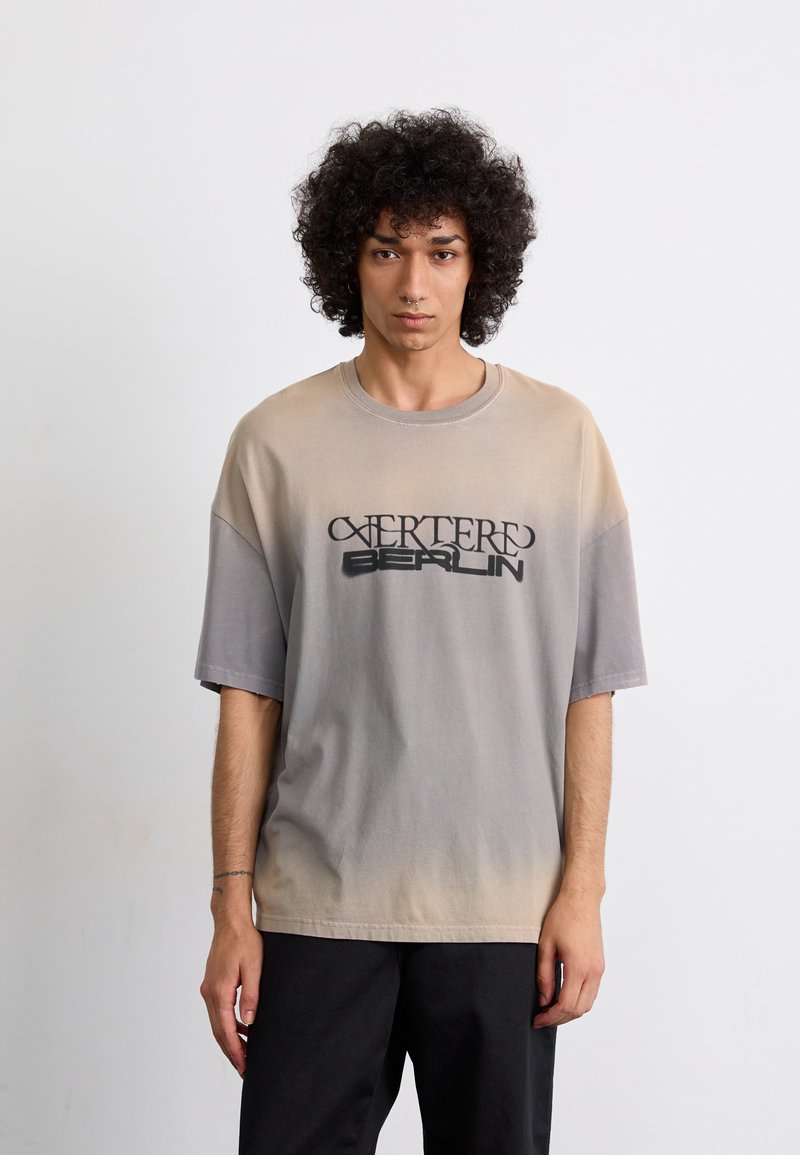 Oversized gradient t-shirt, beige to gray, features a graphic print reading "EXTERED BERLIN." Made of soft cotton with a relaxed fit.