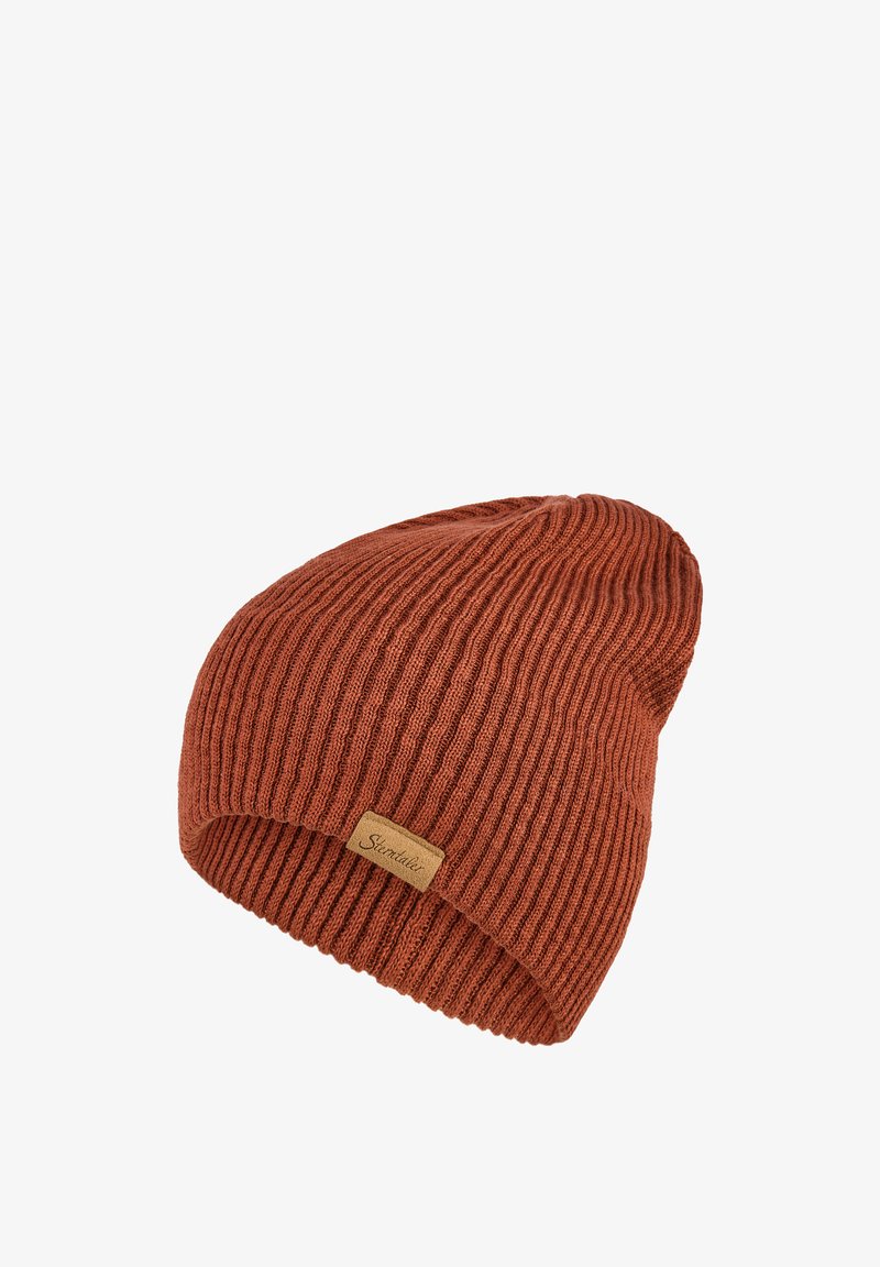 Ribbed beanie in burnt orange, made of soft fabric. Features a fold-over cuff and a small stitched logo tag on the side.