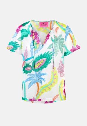 White short-sleeve blouse with colorful tropical floral print, V-neck with ties, and a pink brand label inside the collar.