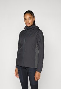 Schwarze wasserdichte Jacke mit einem Reißverschluss vorne, Kapuze und strukturierten Akzenten. Sie verfügt über mehrere Einsätze und ein leicht tailliertes Design für Beweglichkeit.