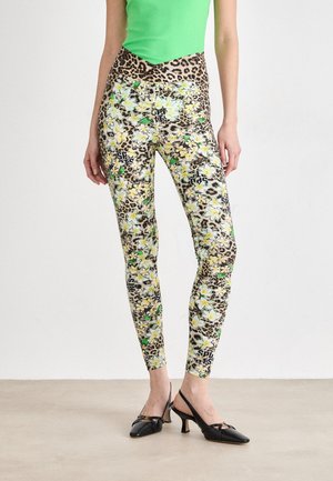 Leggings taille haute avec un motif floral en vert et jaune, contrasté par un design à imprimé léopard ; accompagnés de chaussures à talons noires.