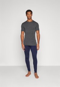 T-shirt ajustado de mangas curtas cinza, combinado com leggings azul-marinho. Textura suave, design simples e sem padrões ou acessórios visíveis.