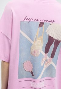 Άτομο με ρούχα τένις που κρατάει μια διχτυωτή τσάντα με μπάλες, στέκεται σε γήπεδο με ρακέτα· το κείμενο «συνέχισε να κινείσαι» πάνω από την εικόνα.